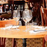 Une table de restaurant avec verres à vin et couverts préparés, avec tons vifs